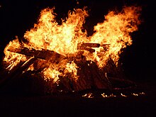 Dans le noir, des un feu orange et rouge brûle des buches