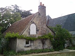 Photographie en couleurs d'une maison à pierre de couleur beige et à toit aux pentes douces, un corps de logis en arrière-plan.