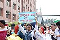 A female protester holding sign reading "মানবে না হার এই গণজোয়ার" ("This mass wave won't give up")