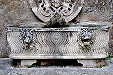 Roman strigillated lion-head lenos sarcophagus, in current use as a water basin. Ca. 260 AD. Palazzo Mattei, Rome. Palazzo Mattei strigillated lion-head sarcophagus.jpg