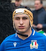 Joueur de rugby de face avec un maillot bleu et un casque jaune et noir sur la tête.