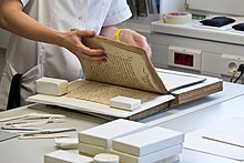 A book conservator examining pages of a bound volume RDZ des Historischen Archivs der Stadt Koln - Gefriertrocknungsanlage und Archivgut-2286.jpg