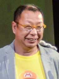 Portrait d'un homme brun souriant de type asiatique, portant des lunettes.