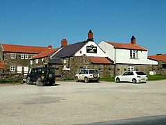 A collection of buildings that make-up the Lion Inn, with vehicles in front