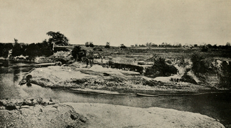 The locality of the Pithecanthropus find, on the Solo River, near Trinil, Java. The two white squares show where the femur (left) and the skullcap (right) were discovered. Their discovery near flowing water was one of the many sources of controversy that surrounded the fossils. The most ancient skeletal remains of man Plate 1.png