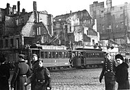 Intersection of Marszałkowska Street and Aleje Jerozolimskie Street in Warsaw during German occupation. Visible tramway #3 with a billboard "Kamea woda kwiatowa". Behind it ruins of destroyed in 1939 townhouse at Marszałkowska 98/al. Jerozolimskie 33 streets.