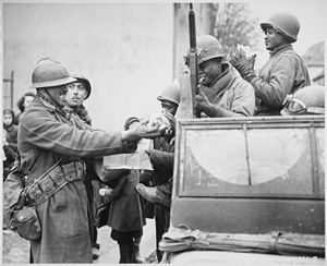 "Twee lachende Franse soldaten vullen de handen van Amerikaanse soldaten met snoep, in Rouffach, Frankrijk, na de sluiting van t - NARA - 531247.jpg