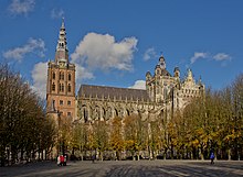 Vue en extérieur d'une cathédrale gothique, clocher en briques et nef en pierres grises.