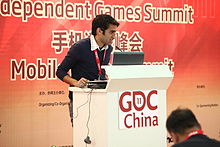 A man standing behind a white podium with GDC China 11 written on it. A red banner behind him reads Independent Games Summit as well as Chinese characters.