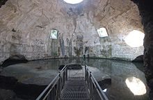 Bare concrete dome interior today called the Temple of Mercury with two square windows halfway up the dome on the far side, a circular oculus at the top, and a water level that reaches up to the base of the dome