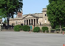 The frontage of a neoclassical buildings seen between trees