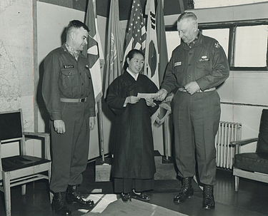 LTG Claude B. Ferenbaugh (right), deputy Eighth Army commander, presents a check for $595 to Mrs. On Soon Whang, director of the Orphans' Home of Korea, Cheju Island. Chief of staff BG Dwight E. Beach observes. The check is the semi-annual interest on the orphanage's perpetual support trust fund. Stars and Stripes, March 1, 1955 Claude B. Ferenbaugh 2.jpg