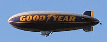 Cigar-shaped blimp with "Good Year" written on its side.