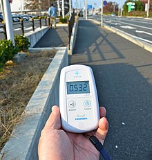 Hand-held scintillation counter reading ambient gamma dose. The position of the internal detector is shown by the cross Minamisoma Radiation 2011-11.jpg