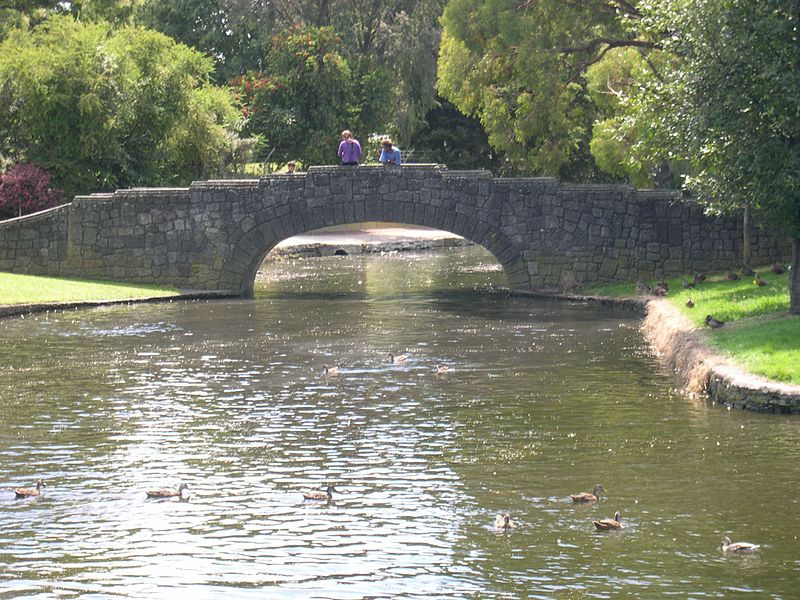 File:Old stone bridge with water flowing gently by the park.jpg