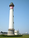 Le phare de Ouistreham avec, en arrière plan, un car-ferry de la Brittany Ferries sur la ligne Caen/Ouistreham-Portsmouth.