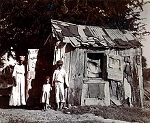 People standing outside shanty housing