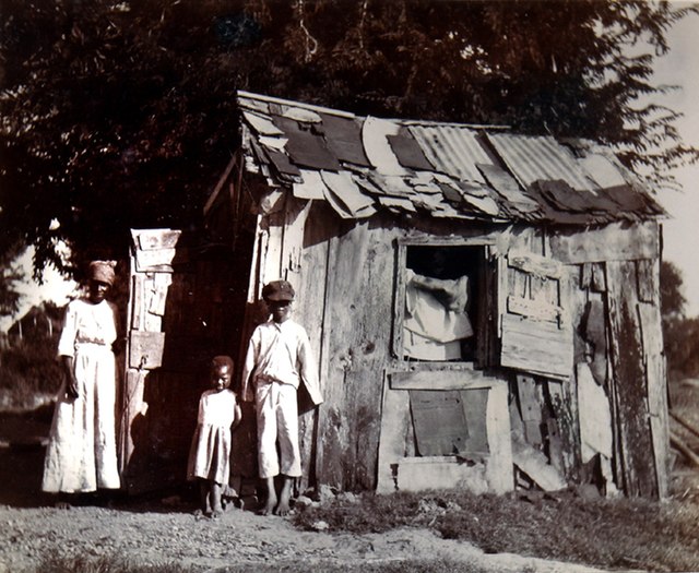 People standing outside shanty housing