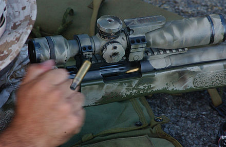 A Marine manually extracts an empty cartridge and chambers a new 7.62×51mm round in his bolt-action M40A3 sniper rifle. The bolt handle is held in the shooter's hand and is not visible in this photo.