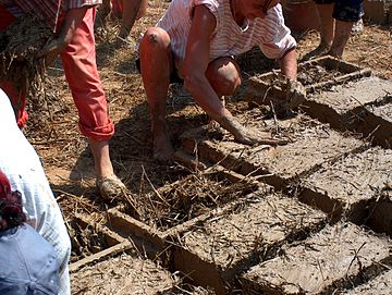 Mixing mud and straw in brick frames