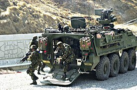 Soldats se déployant d'un Stryker de l'US Army qui effectue un tir de suppression pendant un exercice.