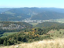 Paysage de moyenne montagne avec localité en fond de vallée.