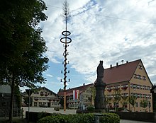 Kirchplatz samt Rathaus und benachbarten Gebäuden. Maibaum in der Mitte des Platzes