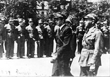 Dva muži v uniformách hledí na nastoupenou jednotku