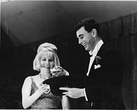 Charles Robinson demonstrating his skill as a magician, with the assistance of his wife Joan, at a late 1960s–early 1970s fundraiser.