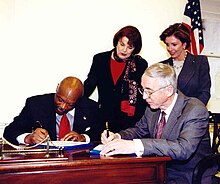 Mayor Brown signing legislation in 2002, flanked by Dianne Feinstein, Nancy Pelosi, and Gordon England Congresswoman Pelosi at the Signing of the Transfer of the Hunters Point Naval Shipyard (7677795096).jpg