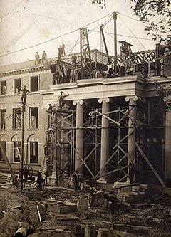 Construction of Wallace Hall, 1908. Its entrance is modeled after the east portico of the ancient Erechtheion of the Athenian Acropolis. The building houses historic classrooms that played a part in educating all living alumni. Construction of Wallace Hall, Monmouth College, 1908.jpg