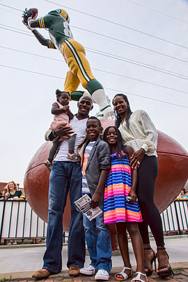 Donald Driver, his wife and three kids standing in front of the Receiver statue