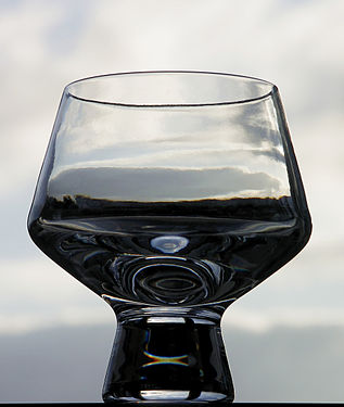 Cognac glass against the sky and clouds