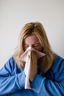 A woman blowing her nose (expelling snot) into a handkerchief Influenza.jpg