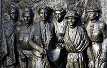 Close de escultura de bronze em baixo-relevo com seis mulheres agrupadas juntas com expressões calorosas e sérias, duas delas usam chapéus e todas usam blusa e saia com trajes da época.  Além disso, Meri Te Tai Mangakāhia à esquerda também tem uma capa.  Apresentando líderes do movimento sufragista na Nova Zelândia.  Da esquerda para a direita: Meri Te Tai Mangakāhia, Amey Daldy, Kate Sheppard, Ada Wells, Harriet Morison e Helen Nicol.