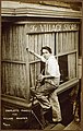 Portrait of Charlotte Powell standing on a ladder and painting the exterior of The Village Store, Sheridan Square, ca. 1915-1926. (9564430896).jpg