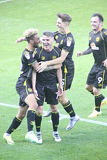 Ryan Lowe is congratulated by teammates after scoring the opening goal for Crewe Alexandra in a 2-1 win at Stevenage (6 August 2016). Ryan Lowe celebrates.jpg