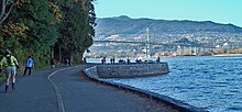 Park visitors walk, bike, roll, and fish on the seawall. The Lions Gate Bridge is in the background. Stanley Seawall.jpg