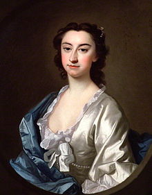 Dark-haired, dark-eyed woman with a large nose, wearing a low-cut white blouse