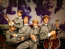 photographie en couleurs de quatre personnes assises sur un canapé, jouant de la musique.