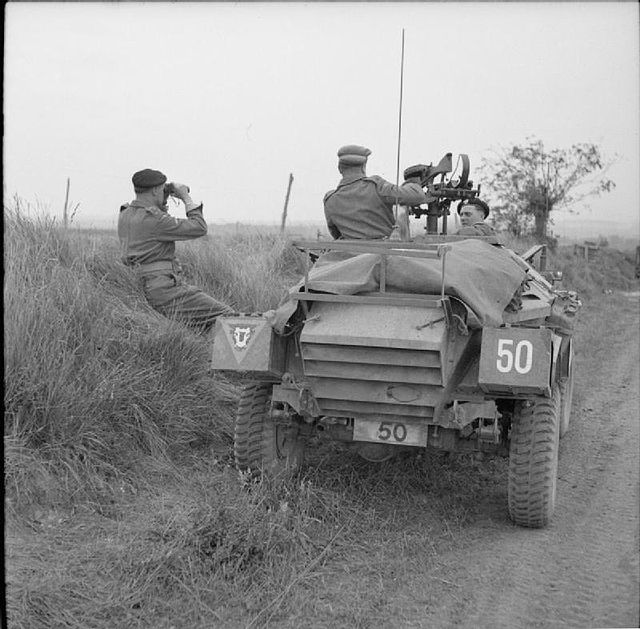 Brigadier N. W. Duncan of the 30th Armoured Brigade watches the attack on Caen from beside his Humber Scout Car outside Beuville, 8 July 1944.