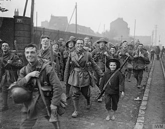 Men of the 8th (Liverpool Irish) Battalion of the King's (Liverpool Regiment) entering Lille, France, 18 October 1918. Note a barefooted French boy with a rifle, clearly given to him by a smiling British soldier on his right. The Hundred Days Offensive, August-november 1918 Q9574.jpg