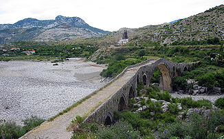 Ottoman bridge Ura e Mesit over the here dry river bed of the Kir