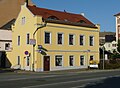 Wohnhaus in offener Bebauung und Ecklage, mit Mauerumfriedung, Hintergebäude und Brunnen im Hof