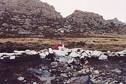 A cross amongst rocks painted white and a mountain in the background