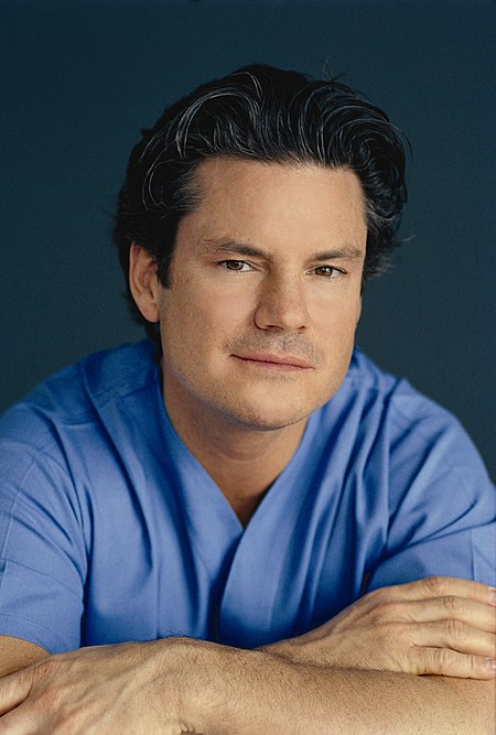 Dr Mulholland Arms Crossed In Scrubs.jpg