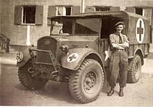 FAU ambulance and driver, Germany, 1945 Friends Ambulance Unit ambulance driver, with his vehicle in Wolfsburg, Germany.jpg