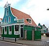 Houten huis, aan de voorzijde voorzien van ingezwenkte voorschot met rijke bekroning in Lodewijk xvi-stijl, guirlande en zijmeanders