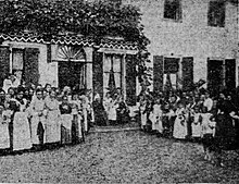 A large group of students standing in front of a mansion