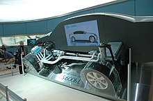 Cutaway hybrid car showing electrical connections; auto show display backdrop.